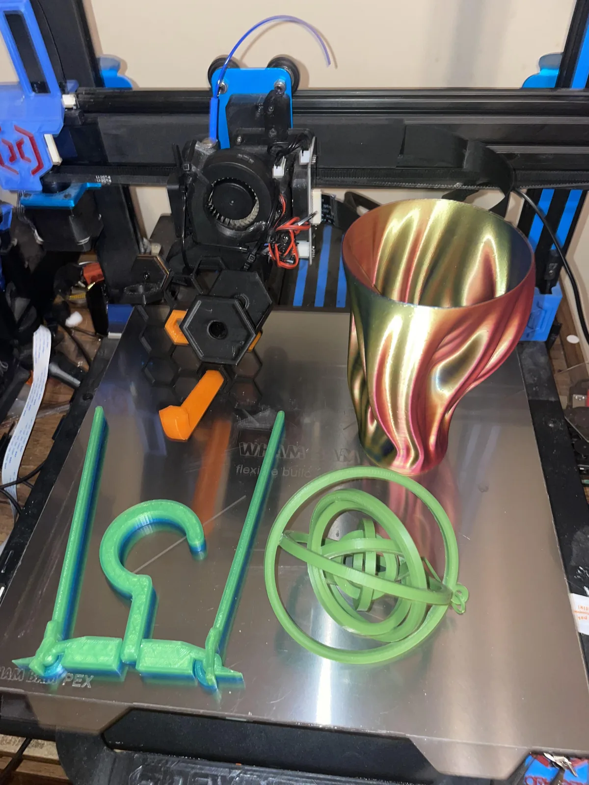A print bed with a silk multicolour vase, a printed hook and a green gyroscope