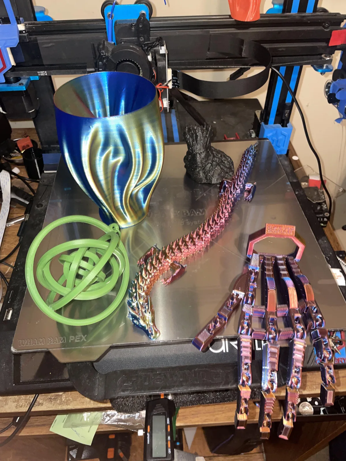 A printer bed with a vase, a gyroscope ring, an articulated dragon and an articulated hand
